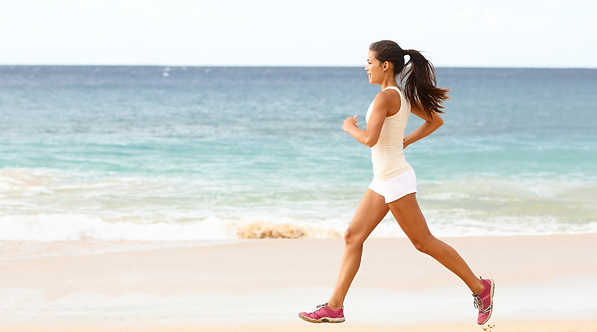 Fit woman jogging along a sandy beach toward her summer weight loss goals
